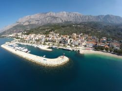 La cittadina di Tucepi con il porto sull'Adriatico visti dall'alto, Croazia. L'alto massiccio calcareo che circonda Tucepi la protegge dai climi rigidi rendendo la temepratura quasi ...