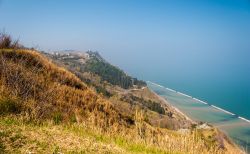 La costa lungo Monte San Bartolo nei pressi di Pesaro: sullo sfondo il grazioso borgo medievale di Fiorenzuola di Focara (Marche).
