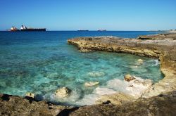 La costa rocciosa di Freeport e una nave cargo in arrivo al porto, isola di Grand Bahama.


