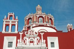 La cupola della chiesa di San Domenico a Puebla, Messico, con i suoi particolari architettonici che risaltano sulla facciata rossa.



