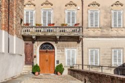 La facciata di un tipico palazzo italiano a La Morra, Cuneo, Piemonte. A impreziosirlo ci sono i fiori sul balcone e il portone d'ingresso in legno
