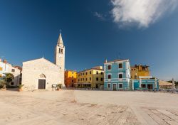 La grande piazza di Fazana con la chiesa dei Santi Cosma e Damiano, Croazia. Dedicato ai santi protettori del villaggio di pescatori istriano, l'edificio religioso ospita un crocifisso gotico ...