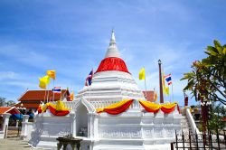 La pagoda bianca addobbata con drappi rossi e gialli al Wat Poramaiyikawas Temple di Nonthaburi, Thailandia.