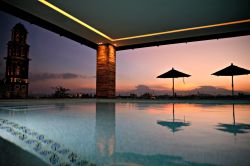 La piscina del Rosewood Hotel di Puebla con gli ombrelloni riflessi nell'acqua e, da un lato, la torre campanaria di San Francesco (Messico) - © Eleni Mavrandoni / Shutterstock.com