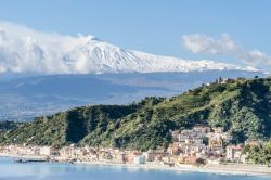 La pittoresca baia di Giardini Naxos con l'Etna innevato sullo sfondo, provincia di Messina, Sicilia.

