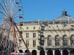 La ruota panoramica di un parco divertimenti a Bayonne, Francia, con il riflesso su un antico palazzo cittadino.
