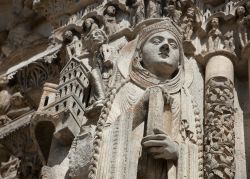 La scultura di un santo che regge un libro nel portale della cattedrale di Chartres, Francia.

