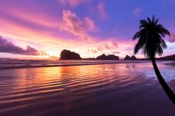 La spiaggia di Pak Meng, provincia di Trang, Thailandia. Sabbia rosa con tramonto sulll'isola nello sfondo.

