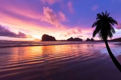 La spiaggia di Pak Meng, provincia di Trang, Thailandia. Sabbia rosa con tramonto sulll'isola nello sfondo.

