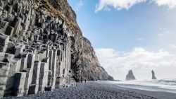 La spiaggia di sabbia nera di Reynisfjara e il monte Reynisfjall, Islanda. Siamo in uno dei principali luoghi di attrazione del paese: ciottoli scuri, colonne di basalto e faraglioni avvolti ...