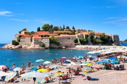 La spiaggia di Sveti Stefan in estate con i turisti in relax (Montenegro) - © photosmatic / Shutterstock.com
