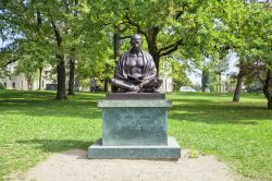 La statua del Mahatma Gandhi nel parco di Ariana a Ginevra, Svizzera. Circondata da alberi e vegetazione rigogliosa, quest'opera in bronzo ritrae Gandhi seduto e intento nella lettura - Sazonov ...