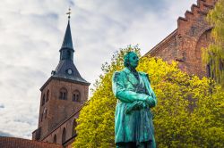 La statua di Andersen con la cattedrale di San Canuto sullo sfondo, Odense, Danimarca. L'edificio religioso è stato chiamato così in onore del re danese Canuto il Santo.

