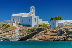 La veduta di una suggestiva chiesa a Sifnos, Grecia. A fare da contrasto all'intonaco bianco degli edifici è il blu del cielo e dell'acqua dell'Egeo.



