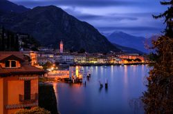 Lago di Como a Menaggio by night, Lombardia. Le luci di abitazioni e palazzi si riflettono sulle acque del Lario creando un'atmosfera ancora più incantevole in questo grazioso angolo ...