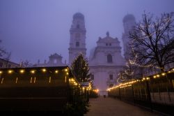 Le bancarelle illuminate del mercatino natalizio di Passau, Germania, dopo la chiusura in una serata di foschia.

