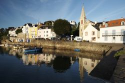 Le case e la chiesa di un villaggio di Belle Ile en Mer, Francia, riflesse nelle acque dell'Oceano Atlantico.
