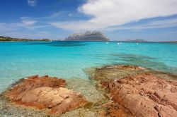 Le rocce rosse e il mare limpido della spiaggia di Porto Istana in Sardegna, la Tavolara sullo sfondo