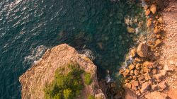 Le scogliere selvagge della costa dell'Algarve nei pressi di Carrapateira, Portogallo. Sono spesso ricoperte di arbusti con macchie gialle e verdi.
