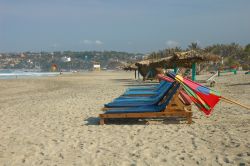 Lettini e ombrelloni colorati su una spiaggia deserta di Puerto Escondido, Messico.
