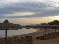 Lettini e ombrelloni di paglia sulla spiaggia di Soma Bay al tramonto. Siamo 40 km a sud di Hurghada, Egitto.

