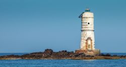 Lo scoglio Mangiabarche e il faro in una giornata di mare calmo a Calasetta in Sardegna