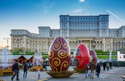 La gente cammina davanti al famoso palazzo del Parlamento di Bucarest a Pasqua, dove è stato organizzato un tradizionale mercatino pasquale - © Cristian Balate / Shutterstock.com ...