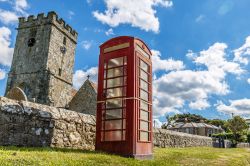 Moderno e antico sull'isola di Wight, Inghilterra: una cabina telefonica e una chiesa in pietra.

