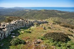Il monte Arcuentu e, sullo sfondo, un tratto della costa di Arbus, Costa Verde, Sardegna. Questa imponente cresta rocciosa si innalza sino a 785 metri di altezza; il nome della montagna deriva ...