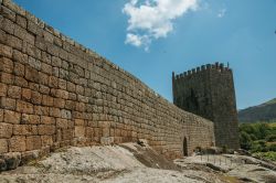 Mura in pietra e torre sulle alture del borgo di Linhares da Beira, Portogallo, fotografate in una giornata estiva di sole.

