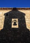 L'ombra del campanile e della campana di San Martino sul muro in pietra di un edificio, Trujillo, con la luce del tardo pomeriggio.

