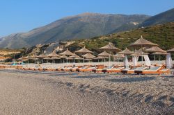 Ombrelloni in riva al mare sulla spiaggia di ghiaia di Dhermi, in Albania