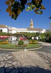 Orange Square a Estepona, Costa del Sol: la piazzetta è fotografata in una giornata di sole con prato all'inglese e fiori colorati.



