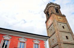 L'orologio del campanile a La Morra, Cuneo, Piemonte. Sullo sfondo, la facciata dai colori vivaci di un antico edificio
