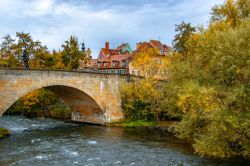 Paesaggio autunnale lungo il fiume Regnitz a Bamberga, Germania. Il ponte in pietra con il monumento alla crocifissione.



