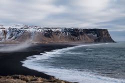 Paesaggio islandese: la famosa spiaggia nera di Vik i Myrdal con i monti innevati.



