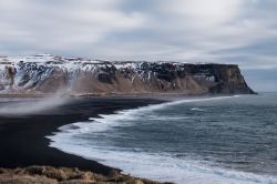 Paesaggio islandese: la famosa spiaggia nera di Vik i Myrdal con i monti innevati.



