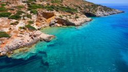 Panorama dall'alto della costa rocciosa di Schinoussa (Grecia) lambita dall'acqua cristallina dell'Egeo.

