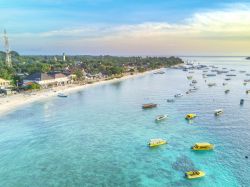 Panorama dall'alto dell'isola di Gili Trawangan all'alba, Indonesia, con decine di barche ormeggiate al largo della costa.
