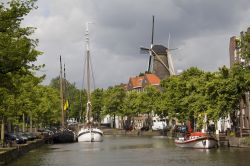 Panorama del canale con le barche e un mulino a vento a Schiedam, Olanda. In questa città dell'Olanda meridionale si trovano i più alti mulini a vento del mondo che raggiungono ...