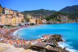 La spiaggia di Camogli affollata durante una calda giornata estiva - il borgo marinaro di Camogli, parte della città metropolitana di Genova, è annoverato tra i più belli ...