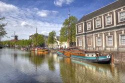Panorama di Schiedam con vecchie imbarcazioni, abitazioni e un mulino a vento in lontananza, Olanda.
