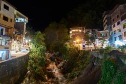 Panorama notturno di Aguas Calientes, Perù. Uno scorcio del celebre villaggio nei pressi di Machu Picchu con le sue costruzioni affacciate sulle viuzze strette e con al centro la cascata ...