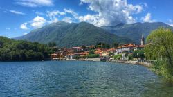 Panorama sul lago di Mergozzo e sulle abitazioni affacciate in una bella giornata estiva, Verbano-Cusio-Ossola, Piemonte.
