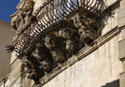 Particolare della facciata barocca di Palazzo Cosentini a Ragusa Ibla, Sicilia, Italia. Uno dei tre balconi dell'edificio celebri per la ricca decorazione delle mensole con figure dai volti ...