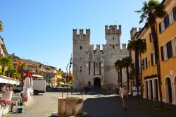 Piazza Castello con la fortezza scaligera a Sirmione, Lago di Garda, Lombardia. Circondato dalle acque del lago, il castello è difeso da tre torri e dal maschio che si innalza per 47 ...