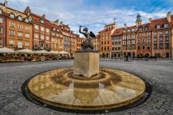 Uno scorcio del centro storico di Varsavia, Polonia. Sulla centrale piazza del Mercato si affacciano edifici a tinte pastello e caffé con tavolini all'aperto.
