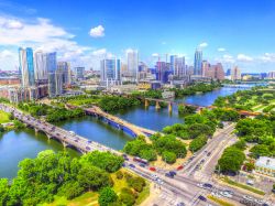 Una pittoresca veduta del centro di Austin con grattacieli, ponti e riflessi nell'acqua del fiume Colorado (Texas, USA).

