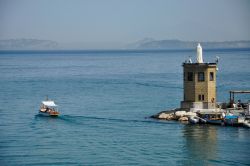 Il porto di Procida con barche e la statua bianca di Santa Maria, baia di Napoli, Campania.


