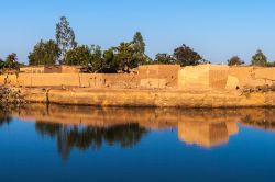 Quartiere orientale di Ouagadougou in una giornata di sole, Burkina Faso (Africa). Le costruzioni in mattoni di fango si rispecchiano nella grande pozza d'acqua in pirmo piano.



